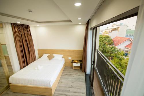 ダナンにあるTONY ESTATES Danang Beach Luxury Apartmentsのベッドとバルコニー付きのホテルルーム