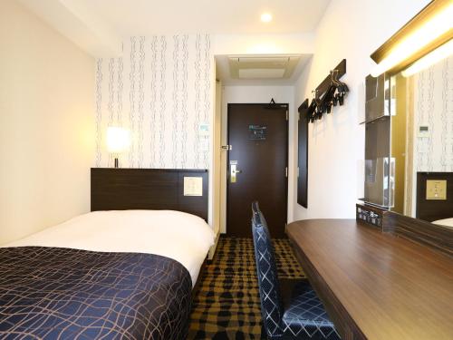 um quarto de hotel com uma cama, uma secretária e uma mesa em APA Hotel Shimbashi Onarimon em Tóquio