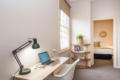 a room with a desk with a laptop and a bed at The Terraces Mudgee in Mudgee