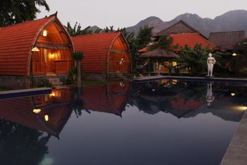 a person standing next to a swimming pool in a resort at Kubu Padi Wooden House in Pemuteran