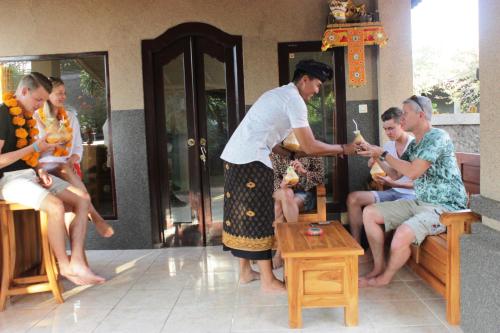 a woman is giving a group of people a drink at Kubu Padi Wooden House in Pemuteran