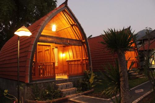 a small house with a large arched roof at Kubu Padi Wooden House in Pemuteran