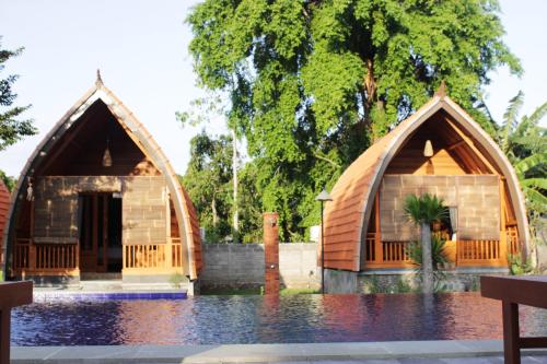 a couple of houses in the water at Kubu Padi Wooden House in Pemuteran