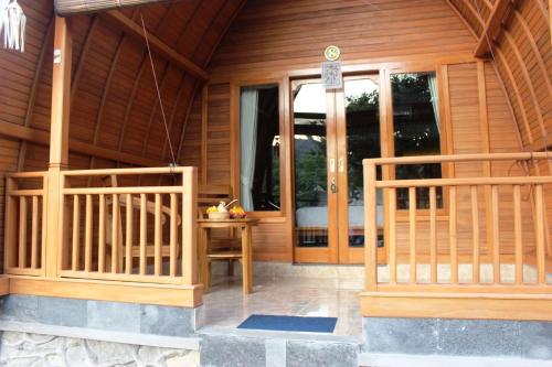 a wooden cabin with a door and a table at Kubu Padi Wooden House in Pemuteran