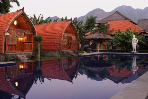 a house with a pool in front of a resort at Kubu Padi Wooden House in Pemuteran