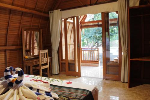 a bedroom with a bed and a sliding glass door at Kubu Padi Wooden House in Pemuteran