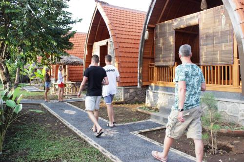 a group of men walking outside of a house at Kubu Padi Wooden House in Pemuteran