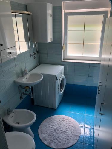 uma casa de banho com um lavatório e uma máquina de lavar roupa em Arcobaleno isolano em Izola