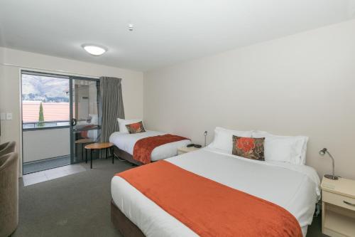 a hotel room with two beds and a balcony at Bella Vista Motel Lake Wanaka in Wanaka