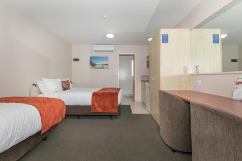 a hotel room with two beds and a desk at Bella Vista Motel Lake Wanaka in Wanaka