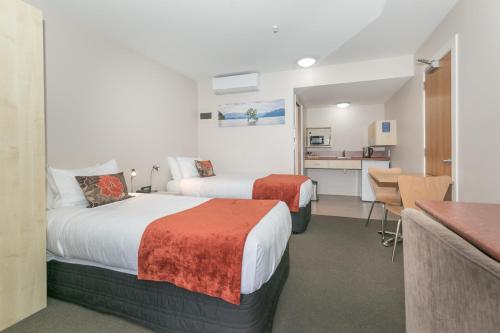 um quarto de hotel com duas camas e uma cozinha em Bella Vista Motel Lake Wanaka em Wanaka