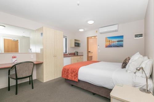 a bedroom with a bed and a desk and a kitchen at Bella Vista Motel Lake Wanaka in Wanaka