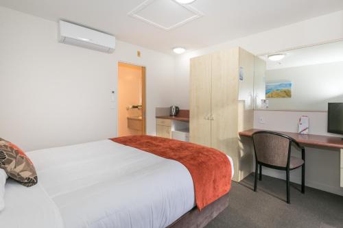 a bedroom with a bed and a desk with a computer at Bella Vista Motel Lake Wanaka in Wanaka