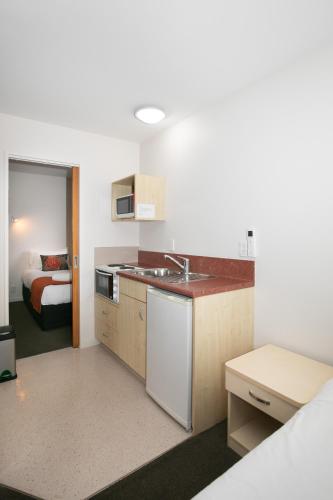 a kitchen with a sink and a room with a bed at Bella Vista Motel Lake Wanaka in Wanaka