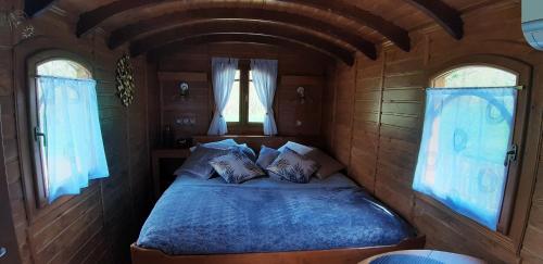 a bed in a small room with two windows at Du Coté de Lacoume in Anla