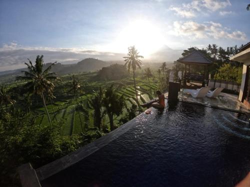 a person sitting in a pool with a view of the mountains at Villa di Bias in Tirtagangga