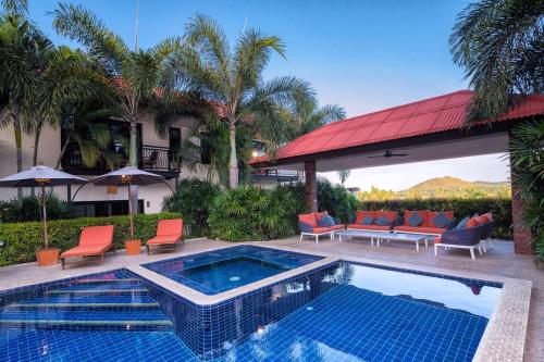 a swimming pool with chairs and a house at Pa Prai Villa at The Plantation in Pran Buri