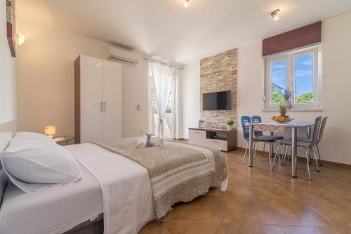 a bedroom with a bed and a table and chairs at Apartments Sestanka in Novalja