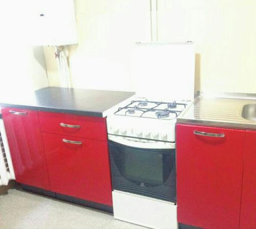 a red kitchen with a stove and red cabinets at Комфортні апартаменти з великим ліжком на Кірова ,поруч 16 лікарня,Дафі in Dnipro