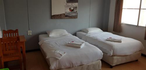 two twin beds in a room with a table at Restaurant & Guesthouse Say Cheese in Hua Hin