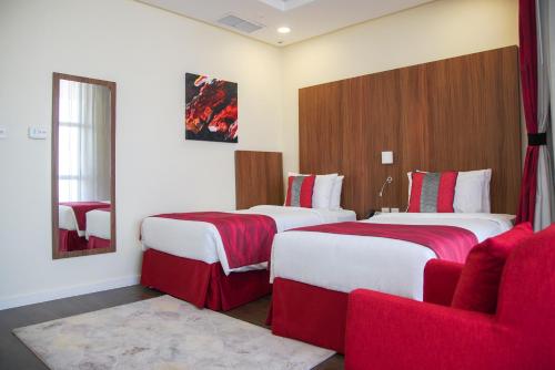 a hotel room with two beds and a red couch at Ramada Encore by Wyndham Kuwait Downtown in Kuwait