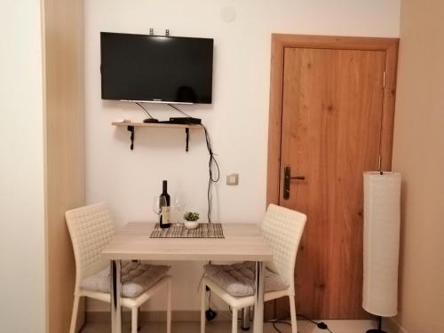 a dining room table with chairs and a television on a wall at Studio Apartman Irena1 in Bijela