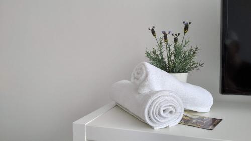 a towel on a table next to a vase with flowers at White Almond Apartment in Budapest