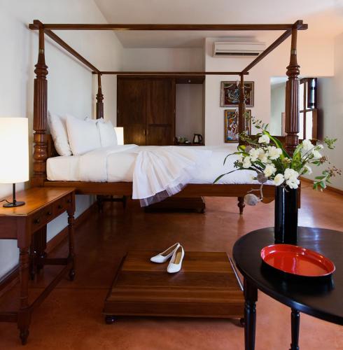 a bedroom with a large bed and a table at Villa Shanti - Heritage Hotel for Foodies in Puducherry
