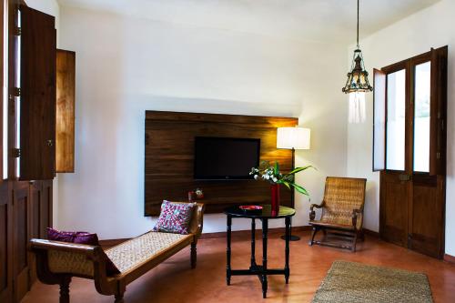 sala de estar con 2 sillas, mesa y TV en Villa Shanti - Heritage Hotel for Foodies, en Pondicherry