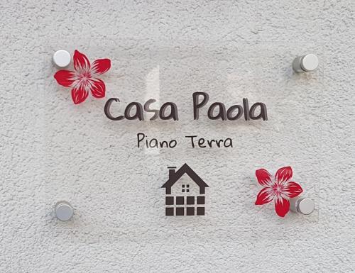 um sinal que diz caa paoola e flores na parede em Casa Paola em Pozza di Fassa