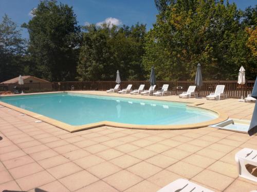 uma grande piscina com espreguiçadeiras e guarda-sóis em Le Pech de Sireuil em Groléjac