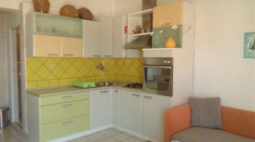 eine kleine Küche mit weißen Schränken und einem orangefarbenen Stuhl in der Unterkunft Bruno apartman in Selce