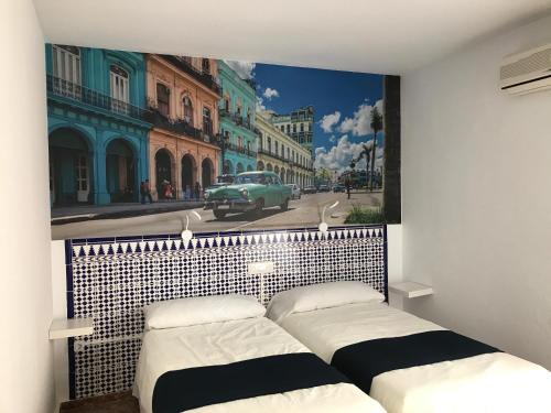 two beds in a room with a picture of a street at Hotel Playa San Cristóbal in Almuñécar