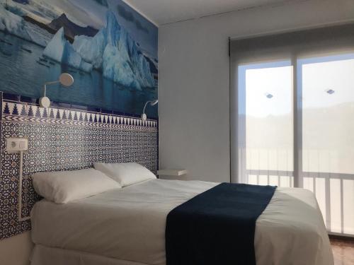 a bedroom with a large bed and a large window at Hotel Playa San Cristóbal in Almuñécar