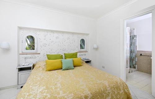 a white bedroom with a large bed with yellow pillows at Casa Gaia in Capri