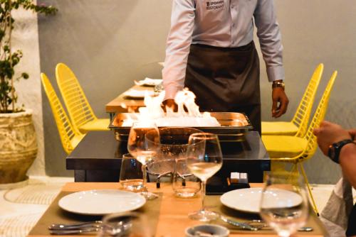 a person standing behind a table with a table with wine glasses at Illyrian Boutique Hotel in Sarandë