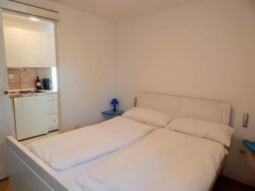 ein weißes Bett in einem kleinen Zimmer mit einer Küche in der Unterkunft Oaza in Krk