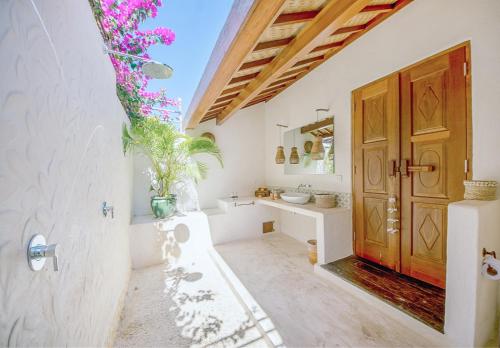 uma casa de banho com paredes brancas e uma porta de madeira em Mule Malu Tropical Stay em Uluwatu