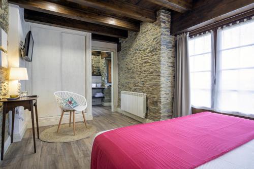 a bedroom with a pink bed and a chair at Hotel Rural La Sobreisla in Puerto de Vega