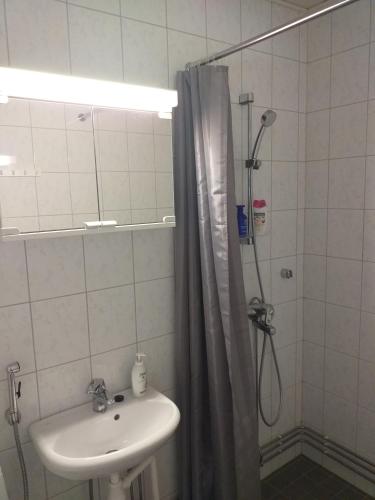 a bathroom with a sink and a shower with a shower curtain at Huoneistohotelli Teekki in Muuruvesi