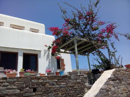 a white house with flowers on a stone wall at Cycladic House in Vari