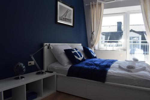 a bedroom with blue walls and a bed with a window at Apartament Silence Baltic Róża Wiatrów in Pobierowo