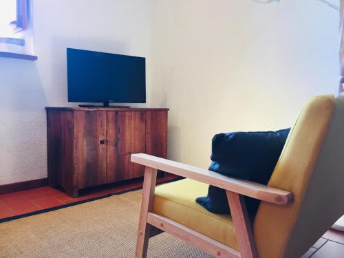 a room with a chair and a tv on a cabinet at Vigna del Poggio in Anghiari