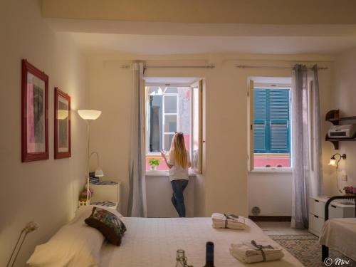 a woman looking out the window of a bedroom at Rundanina Village Life Studio in Vernazza