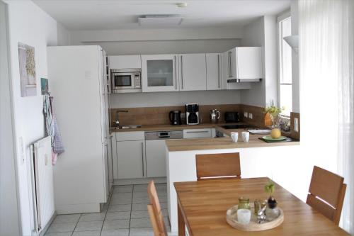eine Küche mit weißen Schränken und einem Holztisch in der Unterkunft Ferienwohnung Bartling am Bodensee in Friedrichshafen