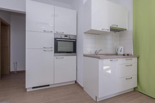 a kitchen with white appliances and a green wall at Apartmani Jadranka in Starigrad-Paklenica