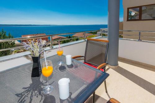 a table on a balcony with two glasses of orange juice at Apartmani Jadranka in Starigrad-Paklenica