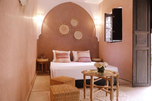una camera con un letto con un tavolo e specchi di Riad l'Oiseau du Paradis a Marrakech