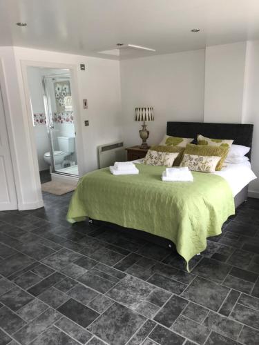 a bedroom with a large bed with a green blanket at Garfield Guesthouse in Dingwall