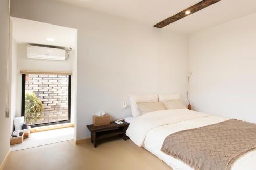 a white bedroom with a bed and a window at Hyuhyudang in Gyeongju